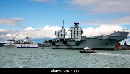 La portaerei HMS Prince of Wales attraccata nel porto di Portsmouth con navi della polizia che pattugliano le acque agosto 2023 - Hampshire, Inghilterra, Regno Unito Foto Stock