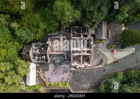 Himley Road, Himley, 6 agosto 2023: L'edificio dopo l'incendio di domenica prima di essere demolito. I resti bruciati del pub Crooked House che è stato acceso intorno alle 22 di sabato sera. - West Midlands e Staffordshire Fire and Rescue Service sono stati chiamati alle 22 di sabato sera, dopo che la Crooked House è stata incendiata. L'ex boozer si trovava a Himley (Staffordshire) vicino alla città di Dudley. L'incendio ha strappato il pub wonky del XVIII secolo che era stato commercializzato per 192 anni fino alla sua chiusura nel mese di luglio. L'edificio vantava un effetto pendente unico che ha causato diversi optamenti Foto Stock