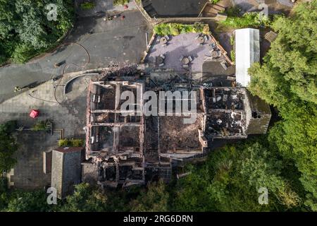 Himley Road, Himley, 6 agosto 2023: L'edificio dopo l'incendio di domenica prima di essere demolito. I resti bruciati del pub Crooked House che è stato acceso intorno alle 22 di sabato sera. - West Midlands e Staffordshire Fire and Rescue Service sono stati chiamati alle 22 di sabato sera, dopo che la Crooked House è stata incendiata. L'ex boozer si trovava a Himley (Staffordshire) vicino alla città di Dudley. L'incendio ha strappato il pub wonky del XVIII secolo che era stato commercializzato per 192 anni fino alla sua chiusura nel mese di luglio. L'edificio vantava un effetto pendente unico che ha causato diversi optamenti Foto Stock