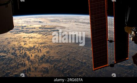 La stazione spaziale Internazionale orbita sopra la Terra sotto forma di raggi di sunglint sul Mare delle Filippine durante un'alba orbitale. Foto Stock