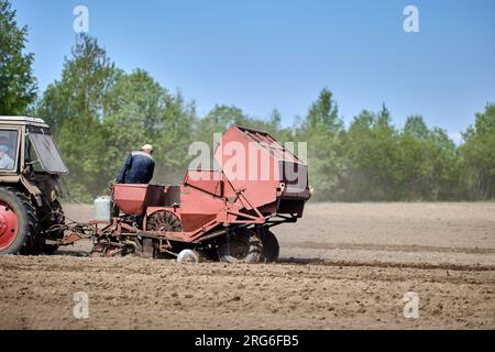 Terreni agricoli durante la piantagione di patate con piantatrice di patate agganciata al trattore. Foto Stock