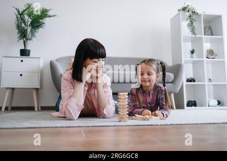 Donna e bambino che giocano a un gioco da tavolo con blocchi sul pavimento Foto Stock