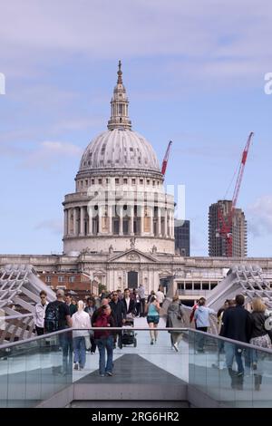 Turisti che attraversano il Tamigi sul Millennium Bridge di fronte alla Cattedrale di St Paul a Londra, Inghilterra Foto Stock