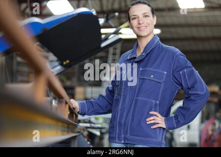 donna operaia in magazzino che posa davanti alla telecamera Foto Stock