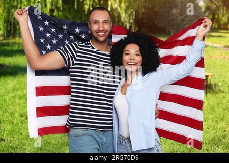 4 luglio - giorno dell'indipendenza dell'America. Felice coppia con la bandiera nazionale degli Stati Uniti nel parco Foto Stock