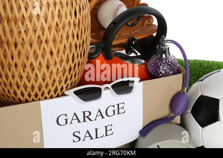 Box con cartello Garage sale e cose diverse su sfondo bianco, primo piano Foto Stock