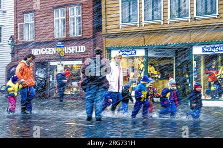 I bambini si divertono con il maltempo sulle strade allagate di Bryggen a Bergen, Norvegia. Foto Stock