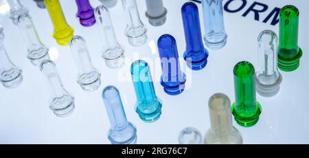 Preforme per bottiglie in plastica PET prima dello stampaggio a soffiaggio. Industria dell'imballaggio. Preforme PET dalla pressa per stampaggio a iniezione delle preforme. Materia prima per bottiglie in PET Foto Stock