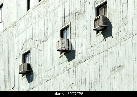 muro astratto con tre finestre e condizionatori d'aria che formano uno schema diagonale Foto Stock