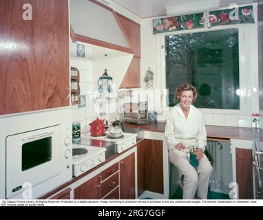 Negli anni '1950 Una bella immagine a colori di una tipica cucina degli anni '1950. È il decennio della prima cucina ben organizzata e organizzata e le sue funzioni di lavorare e avere spazio per gli elettrodomestici come il fornello elettrico, il forno integrato. È seduta sul tipico sgabello da cucina che macina il caffè. La classica macchina per il caffè con aspirapolvere si trova su una piastra riscaldante del fornello elettrico. È diventato popolare negli anni '1950 sia per la preparazione di un buon caffè che per l'intrattenimento della tecnica per la preparazione del caffè. Le pentole di vetro erano comunque molto fragili. Svezia 1958. Conard Foto Stock