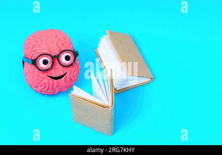 Adorabile personaggio del cervello umano adornato con occhi golosi e occhiali nerd, immerso nella lettura, irradia una passione per la letteratura e la ricerca di Foto Stock