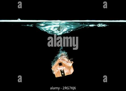 Modello di casa dei giocattoli immerso in acqua su nero. Concetto di assicurazione domestica. Foto Stock