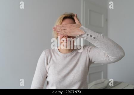 La donna matura triste chiude gli occhi con la mano a casa. Abusi domestici Foto Stock