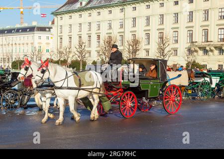 Vienna, Austria - 27 novembre 2010: Autista del fiaker con turisti a Vienna, Austria. Dal 17th secolo, le carrozze trainate da cavalli charact Foto Stock