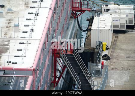 Persone a bordo della chiatta dell'alloggio Bibby Stockholm al porto di Portland nel Dorset, che ospiterà fino a 500 richiedenti asilo. Data foto: Martedì 8 agosto 2023. Foto Stock