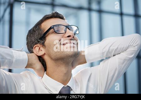 Uomo millenario calmo con gli occhiali sedersi rilassarsi a casa ufficio sul posto di lavoro fare pisolino o sognare ad occhi aperti. Foto Stock