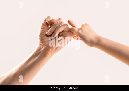 Il bambino aggancia il dito piccolo insieme. Un piccolo dito delle due mani tiene insieme. Mostra amicizia e perdono. Amicizia di generazioni. Padre Foto Stock