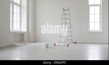 Casa vuota o appartamento con pareti dipinte di bianco, scala a pioli e secchio di vernice Foto Stock