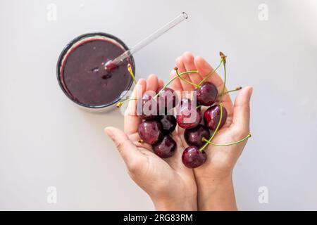 Frullati e ciliegie mature in mani femminili. Foto Stock