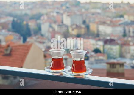 Due bicchieri turchi a forma di tulipano riempito di tè nero caldo con vista sui tetti del distretto di Uskudar sul lato asiatico di Istanbul, Turchia Foto Stock