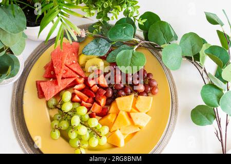 Frutta vibrante splendidamente disposta su un piatto dorato, per creare uno spuntino o un dessert salutare e rinfrescante Foto Stock