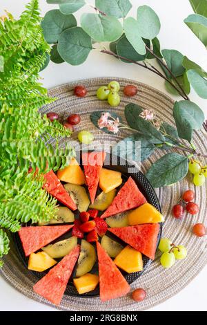 Anguria a fette, cantaloupe, kiwi e fragole disposte su un piatto, creando un piatto di frutta vibrante e rinfrescante, perfetto per una snac sana Foto Stock