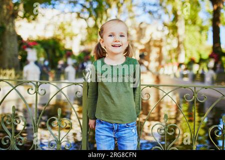 Adorabile bambina in età prescolare che si gode una bella e soleggiata giornata autunnale all'aperto. Buon bambino a piedi nel giardino lussemburghese di Parigi. Attività autunnali all'aperto per Foto Stock