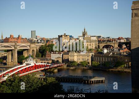 Lo Swing Bridge a Newcastle. Ponte stradale in metallo dipinto di rosso e bianco sul fiume Tyne. Città di Newcastle sullo sfondo con lo stadio di calcio. Foto Stock