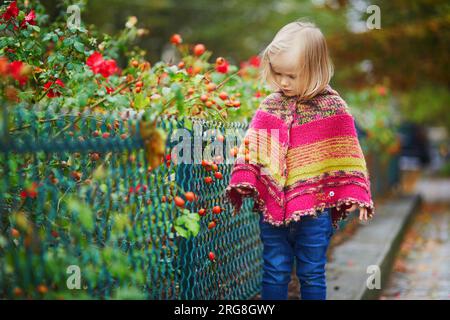 Adorabile bambina che cammina nel parco in un giorno autunnale a Parigi, Francia. Bambini che si divertono all'aria aperta in autunno. Abiti autunnali eleganti e comodi per i bambini Foto Stock