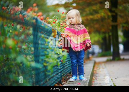 Adorabile bambina che cammina nel parco in un giorno autunnale a Parigi, Francia. Bambini che si divertono all'aria aperta in autunno. Abiti autunnali eleganti e comodi per i bambini Foto Stock