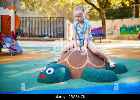 Adorabile bambina al parco giochi in una giornata di sole. Bambini in età prescolare che giocano all'aperto. Attività estive all'aperto per bambini Foto Stock