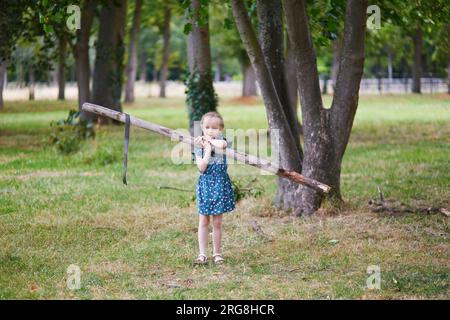 Simpatica bambina in età prescolare che gioca all'aperto nel parco o nella foresta in un giorno d'estate. Attività all'aperto per bambini Foto Stock