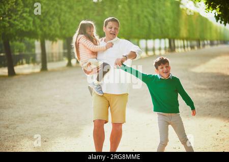 Felice famiglia di tre persone che si sta godendo il loro viaggio a Parigi, in Francia. Padre, figlio e figlia nel giardino delle Tuileries a Parigi. Uomo con bambini che viaggiano in Francia Foto Stock