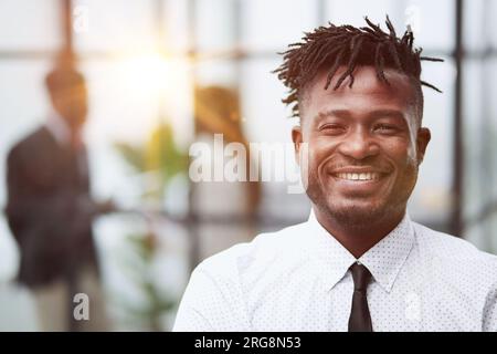 Primo piano ritratto di un bell'uomo d'affari afro-americano sorridente in camicia bianca Foto Stock