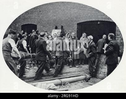 Bickershaw Colliery nel Lancashire, dove il disastro delle miniere di carbone si verificò il 10 ottobre 1932. Un ascensore che trasportava 20 persone cadde nella miniera, uccidendo tutte tranne una persona. Fotografia che mostra la squadra di soccorso che fa uscire uno dei defunti. Foto Stock