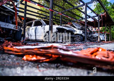 Schwerin, Germania. 8 agosto 2023. Le auto parzialmente bruciate stanno dopo un incendio in un porto. Un totale di sette auto appartenenti ai residenti sono state distrutte nel secondo incendio in 24 ore in un parcheggio. La polizia sospetta incendio doloso e sta indagando sui collegamenti. Credito: Jens Büttner/dpa/Alamy Live News Foto Stock