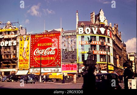 Vista di Piccadilly Circus, Londra, di giorno, con pubblicità per Ever Ready Batteries, Coca Cola, Guinness, Bovril e Schweppes. Foto Stock