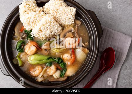 Zuppa di riso glutinosa fritta di pesce con frutti di mare e verdure e riso glutinoso fritto Foto Stock