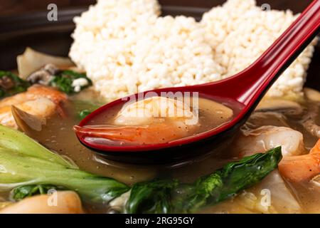 Zuppa di riso glutinosa fritta di pesce con frutti di mare e verdure e riso glutinoso fritto Foto Stock