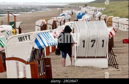 8 agosto 2023, Meclemburgo-Pomerania occidentale, Graal-Müritz: La spiaggia del Mar Baltico è quasi deserta, le sdraio sono in piedi sotto la pioggia. Venti forti e pioggia hanno allontanato i vacanzieri. Foto: Bernd Wüstneck/dpa Foto Stock