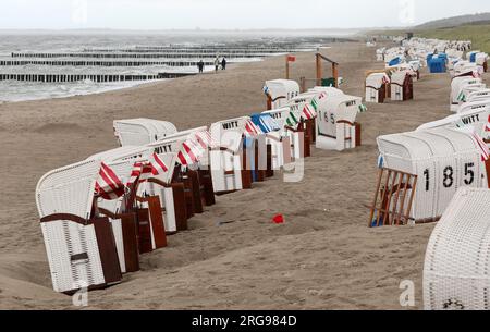 8 agosto 2023, Meclemburgo-Pomerania occidentale, Graal-Müritz: La spiaggia del Mar Baltico è quasi deserta, le sdraio sono in piedi sotto la pioggia. Venti forti e pioggia hanno allontanato i vacanzieri. Foto: Bernd Wüstneck/dpa Foto Stock