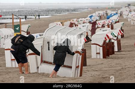 8 agosto 2023, Meclemburgo-Pomerania occidentale, Graal-Müritz: La spiaggia del Mar Baltico è quasi deserta, le sdraio sono in piedi sotto la pioggia. Venti forti e pioggia hanno allontanato i vacanzieri. Foto: Bernd Wüstneck/dpa Foto Stock