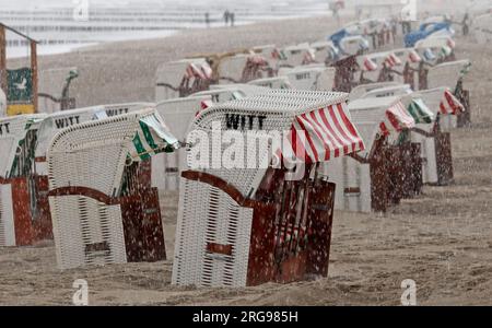 8 agosto 2023, Meclemburgo-Pomerania occidentale, Graal-Müritz: La spiaggia del Mar Baltico è quasi deserta, le sdraio sono in piedi sotto la pioggia. Venti forti e pioggia hanno allontanato i vacanzieri. Foto: Bernd Wüstneck/dpa Foto Stock