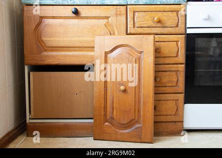 Vecchio armadio da cucina in legno nella cucina con una porta rotta in un appartamento ucraino, mobili da cucina, riparazione di mobili Foto Stock