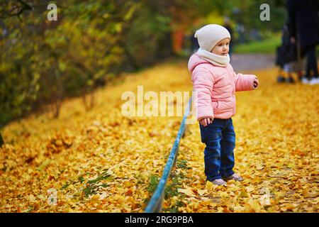 Adorabile e allegra bambina che cammina nel parco Montsouris a Parigi, in Francia. Un bambino felice che si gode la bella giornata autunnale. Attività autunnali all'aperto per bambini Foto Stock