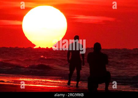 Isola di Palms, Stati Uniti. 8 agosto 2023. I turisti fanno selfie mentre il sole sorge sulla spiaggia in una giornata da record nella zona di Charleston, l'8 agosto 2023 a Isle of Palms, South Carolina. Un'ondata di caldo persistente in tutto il sud degli Stati Uniti continua a portare nella regione un clima estremamente caldo e umido. Crediti: Richard Ellis/Richard Ellis/Alamy Live News Foto Stock