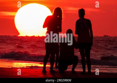 Isola di Palms, Stati Uniti. 8 agosto 2023. I turisti fanno selfie mentre il sole sorge sulla spiaggia in una giornata da record nella zona di Charleston, l'8 agosto 2023 a Isle of Palms, South Carolina. Un'ondata di caldo persistente in tutto il sud degli Stati Uniti continua a portare nella regione un clima estremamente caldo e umido. Crediti: Richard Ellis/Richard Ellis/Alamy Live News Foto Stock