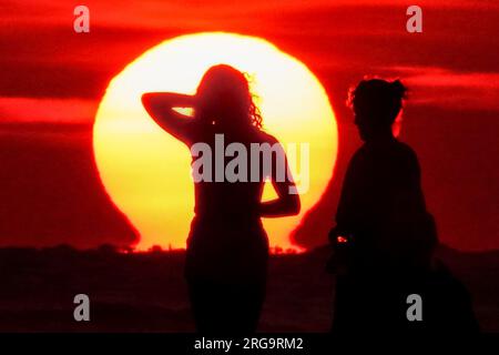 Isola di Palms, Stati Uniti. 8 agosto 2023. I turisti posano per i selfie mentre il sole sorge sulla spiaggia in una giornata da record di caldo e fango nella zona di Charleston, 8 agosto 2023 a Isle of Palms, South Carolina. Un'ondata di caldo persistente in tutto il sud degli Stati Uniti continua a portare nella regione un clima estremamente caldo e umido. Crediti: Richard Ellis/Richard Ellis/Alamy Live News Foto Stock