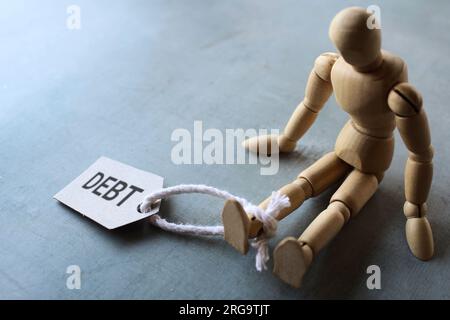 Figura umana di legno e DEBITO DI tag. Spazio di copia per il testo. Finanza, concetto di onere del debito. Foto Stock