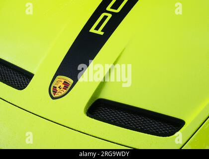 Un primo piano della sezione del cofano di un'auto sportiva tedesca Porsche GT3 verde lime che mostra il logo dell'auto e le prese d'aria anteriori. Foto Stock